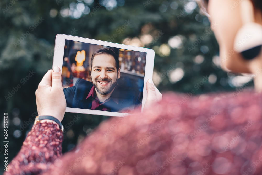 Φωτογραφία Young woman holding a tablet in her hands, having a video call chat with her freelancer boyfriend who is away on business trip