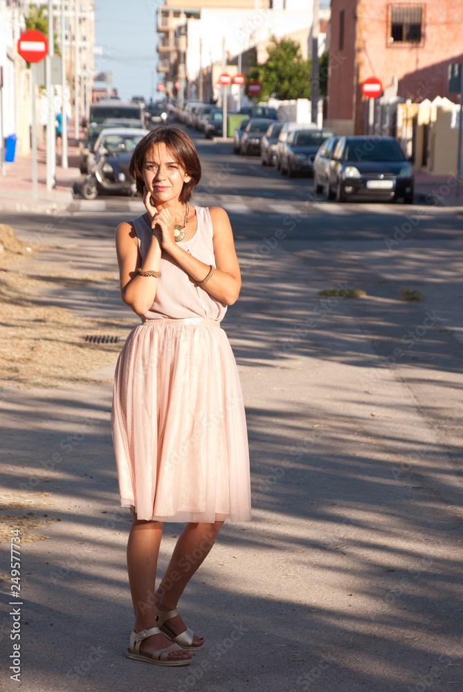 City chic young woman wearing pink dress in street.
