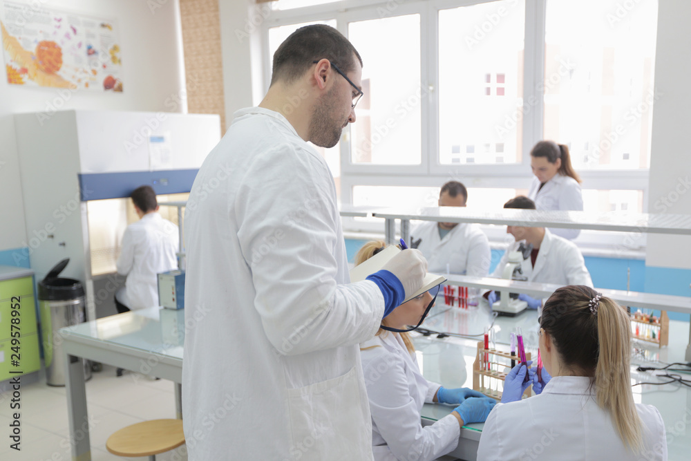 Group of young Laboratory scientists working at lab with test tubes and microscope, test or research in clinical laboratory.Science, chemistry, biology, medicine and people concept. Group of young Laboratory scientists working at lab with test tubes and microscope, test or research in clinical laboratory.Science, chemistry, biology, medicine and people concept.