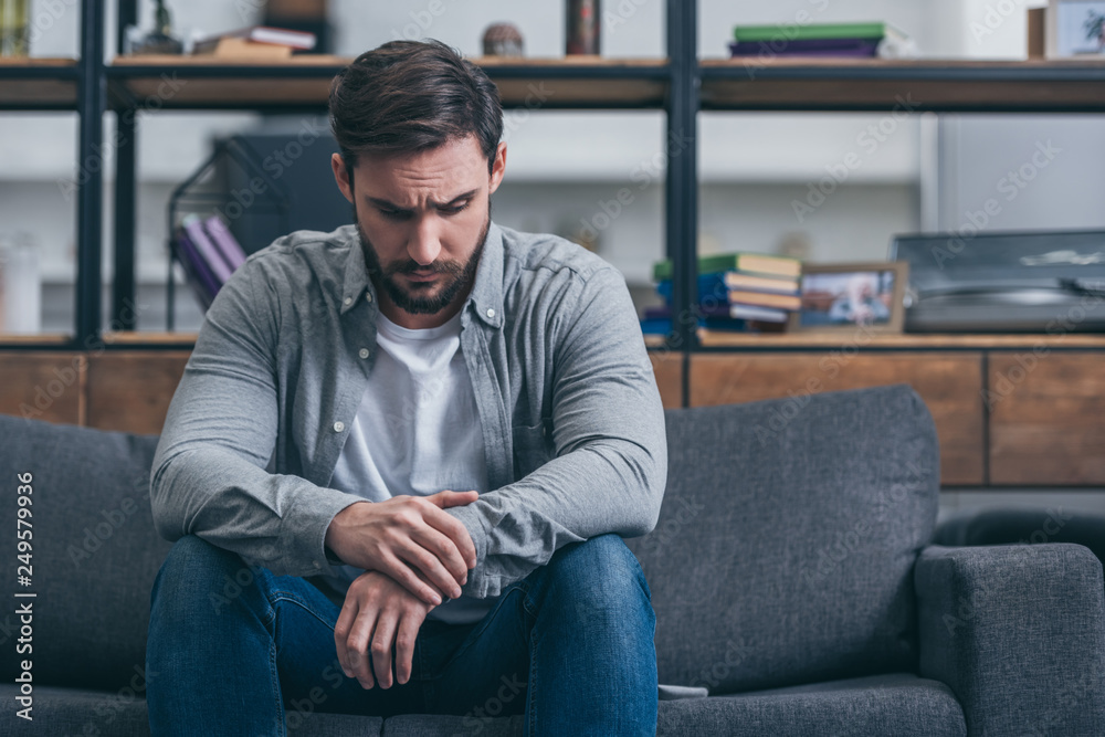depressed man sitting and grieving on couch in living room