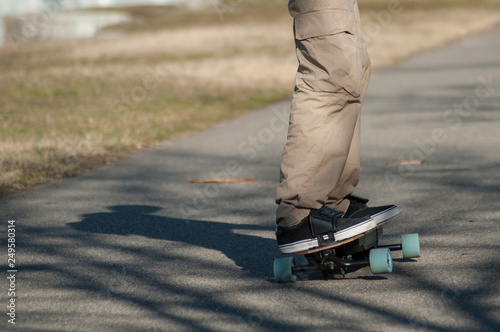 Fototapeta Naklejka Na Ścianę i Meble -  closeup of legs of man on electric skate board on the road