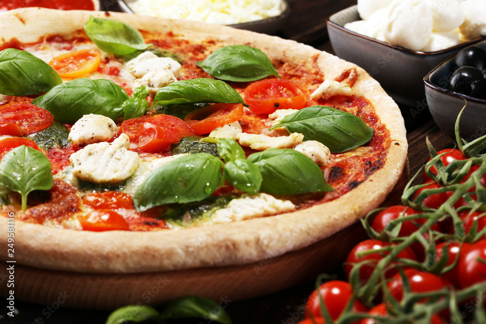Pizza with tomatoes, mozzarella cheese, black olives and basil. Delicious italian pizza on wooden pizza board. Pizza with tomatoes, mozzarella cheese, black olives and basil. Delicious italian pizza on wooden pizza board.