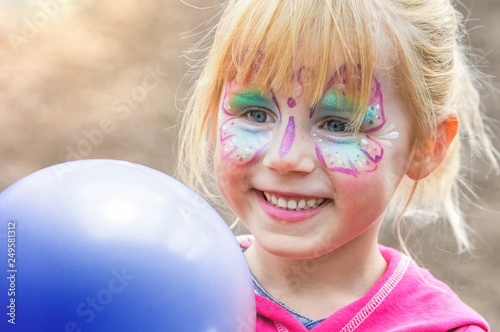 Kinderschminken beim Kinderkarneval auf einem Freizeitpark mit einem Luftballon	