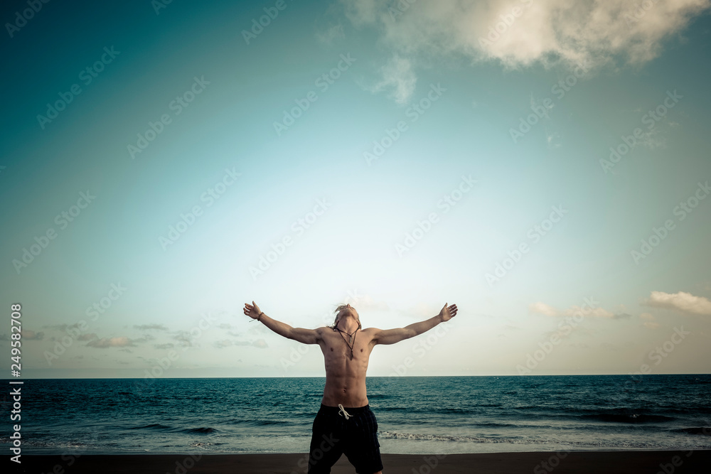 Success and totaly independent lifestyle with caucasian handsome man opening his arms under a blur sky at the beach with ocean in background - concept of travel and enjoying life - happy people Success and totaly independent lifestyle with caucasian handsome man opening his arms under a blur sky at the beach with ocean in background - concept of travel and enjoying life - happy people