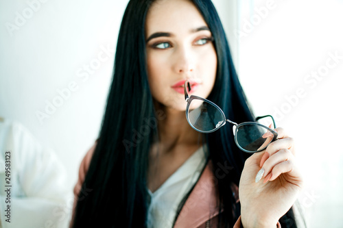 Glasses for vision in the foreground, in the hands of a beautiful girl. Concept photo for advertising glasses
