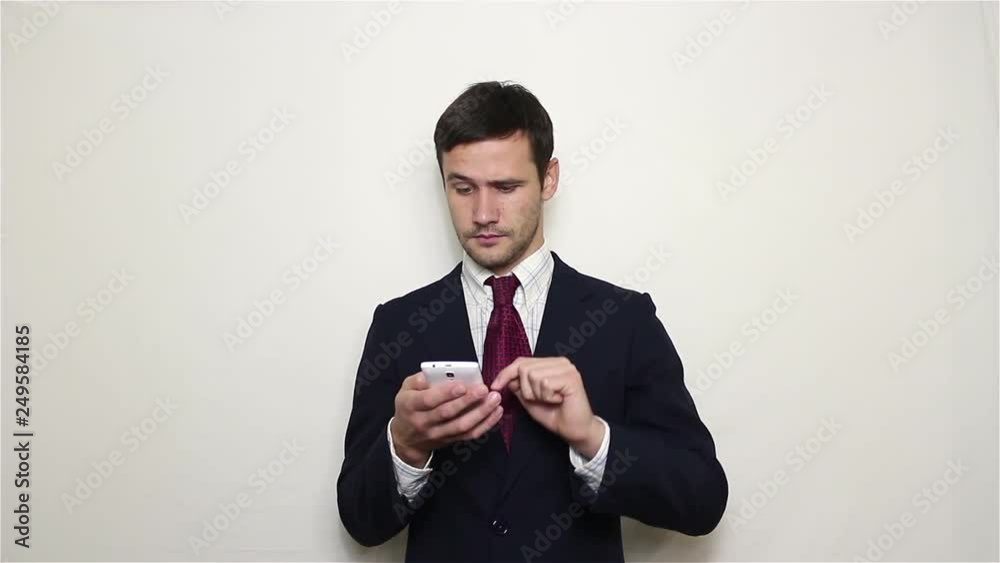 Young handsome businessman is viewing a news feed on his smartphone. Portrait on white background Young handsome businessman is viewing a news feed on his smartphone. Portrait on white background