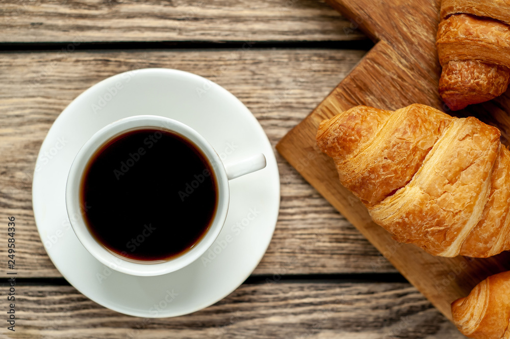 coffee and croissants on wooden cutting board, on wooden background coffee and croissants on wooden cutting board, on wooden background