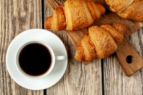 coffee and croissants on wooden cutting board  on wooden background