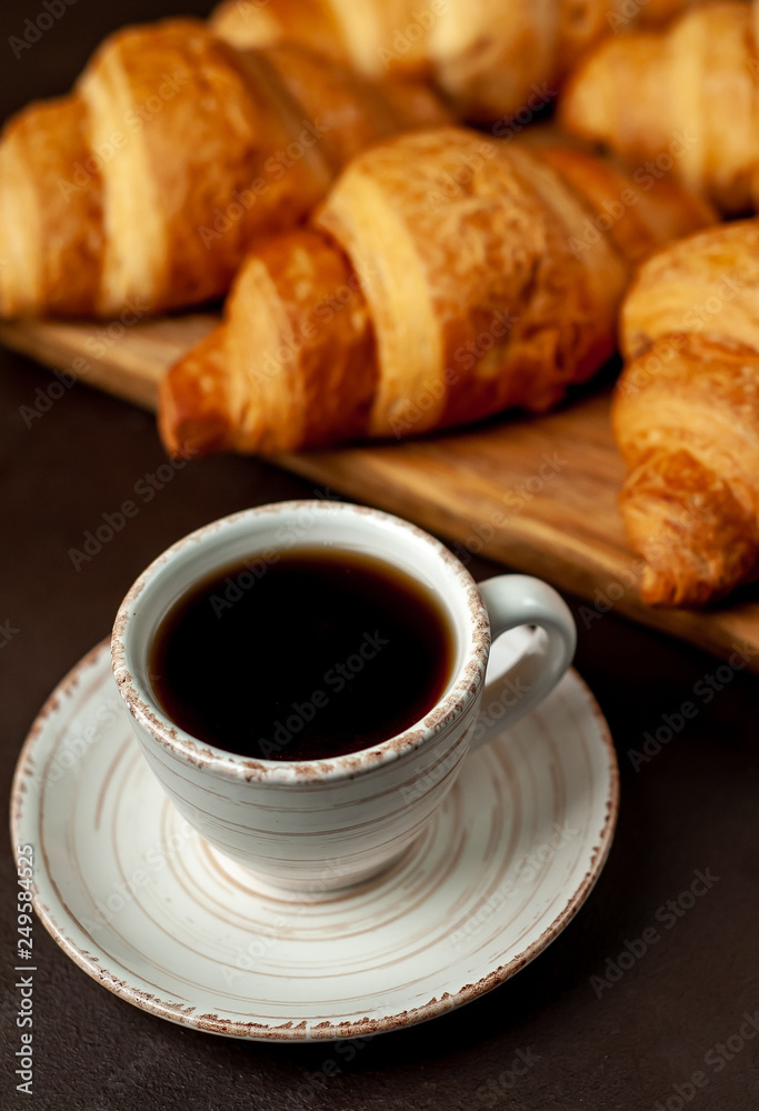 coffee and croissants on wooden cutting board, on the background concrete coffee and croissants on wooden cutting board, on the background concrete