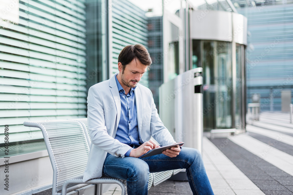 Businessman sitting on a bench, using digital tablet Businessman sitting on a bench, using digital tablet