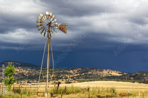 Canvas-taulu Windmill with stormy skies and sunlight on the ground