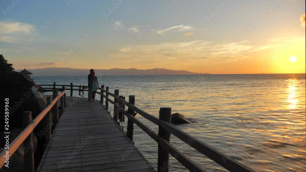 Couple see the sunset overlooking the sea view at sunset time,zoom shot Couple see the sunset overlooking the sea view at sunset time,zoom shot