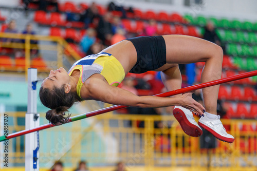 Professional female athlete jumping over bar photo