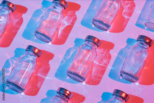 Glass bottle for vaccination with color lighting. Conceptual photo about the danger of viral diseases.