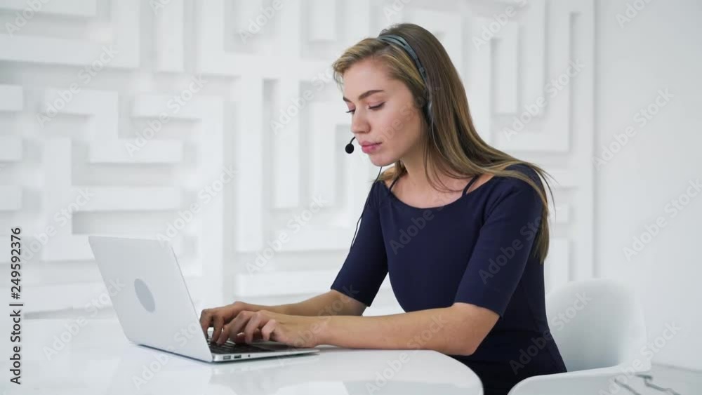 Attractive smiling young dispatcher woman with headset using laptop on abstract maze background. Work and communication concept. HD Real time Attractive smiling young dispatcher woman with headset using laptop on abstract maze background. Work and communication concept. HD Real time