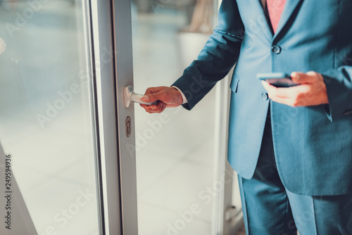 Man opening glass door in his office