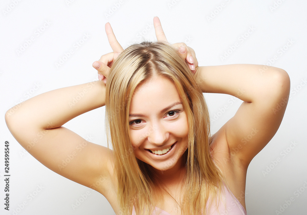 Playful blond girl shows horns