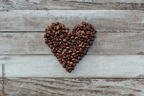 Coffee beans in shape of heart on wooden background