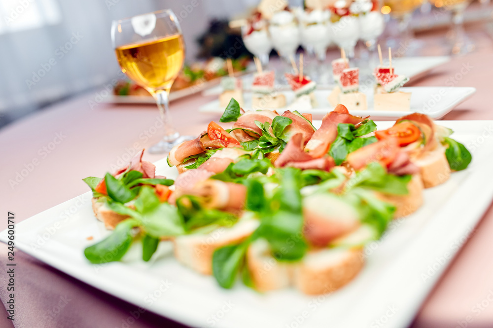 bruschetto with tomato and basil on a plate and a glass of white wine 