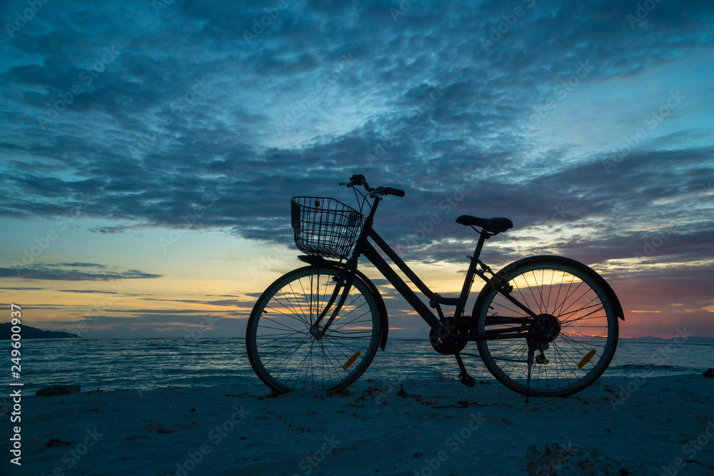Sunset silhouette of vintage bicycle on the beach 