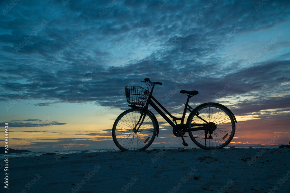 Fototapeta premium Sunset silhouette of vintage bicycle on the beach 