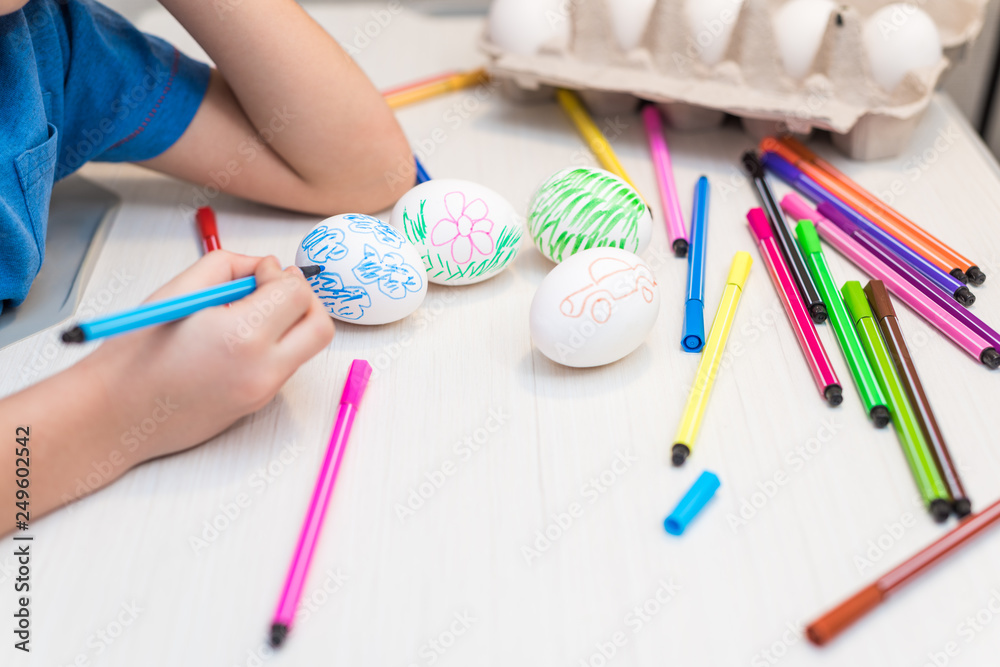 A child will paint Easter eggs with felt-tip pens. Easter ideas. Space for text. Egg tray. Happy easter. A child will paint Easter eggs with felt-tip pens. Easter ideas. Space for text. Egg tray. Happy easter.