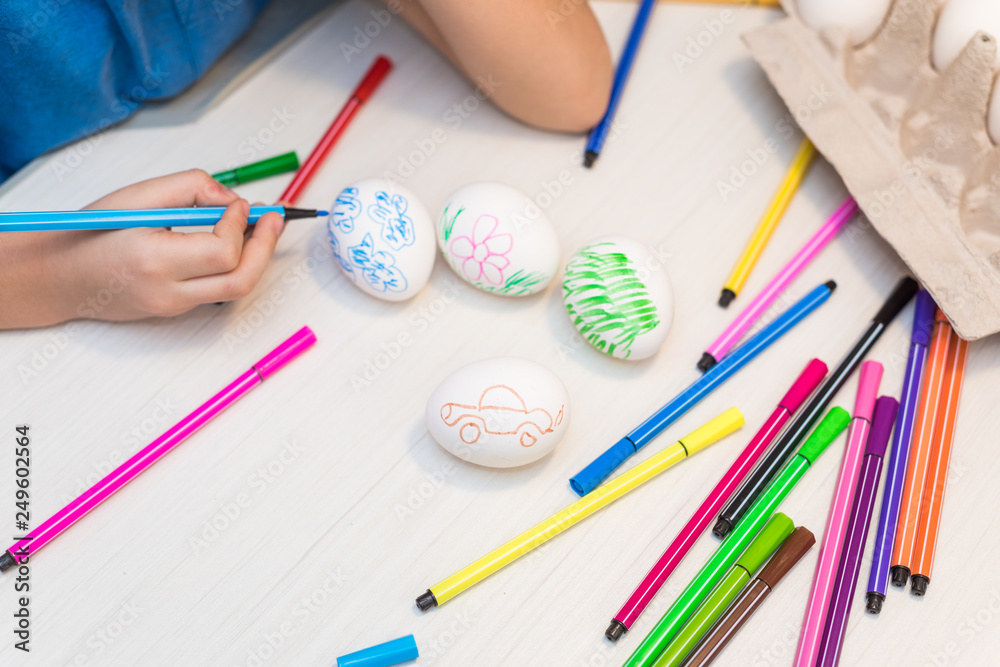 A child will paint Easter eggs with felt-tip pens. Easter ideas. Space for text. Egg tray. Happy easter. A child will paint Easter eggs with felt-tip pens. Easter ideas. Space for text. Egg tray. Happy easter.