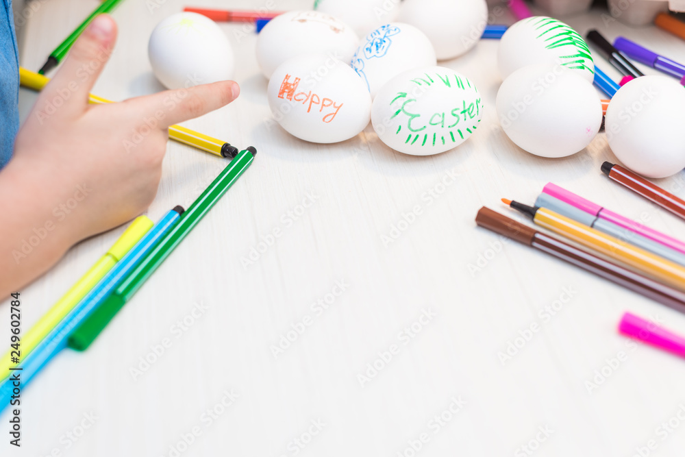 Naklejka premium A child will paint Easter eggs with felt-tip pens. Easter ideas. Space for text. Egg tray. Happy easter.