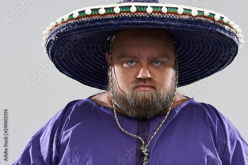 Close up of serious bearded man in sombrero frowning