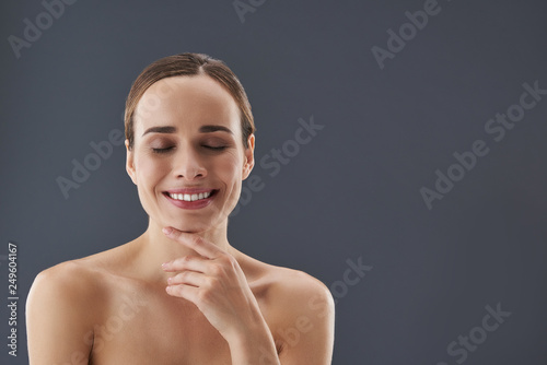 Good-looking young woman with closing eyes touching her chin by fingers