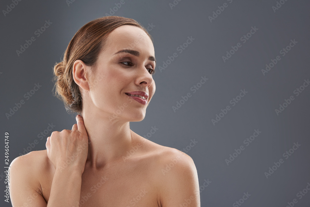 Good-looking woman looking aside and holding hand on neck Good-looking woman looking aside and holding hand on neck