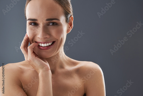 Gorgeous woman looking at camera and holding palm near face