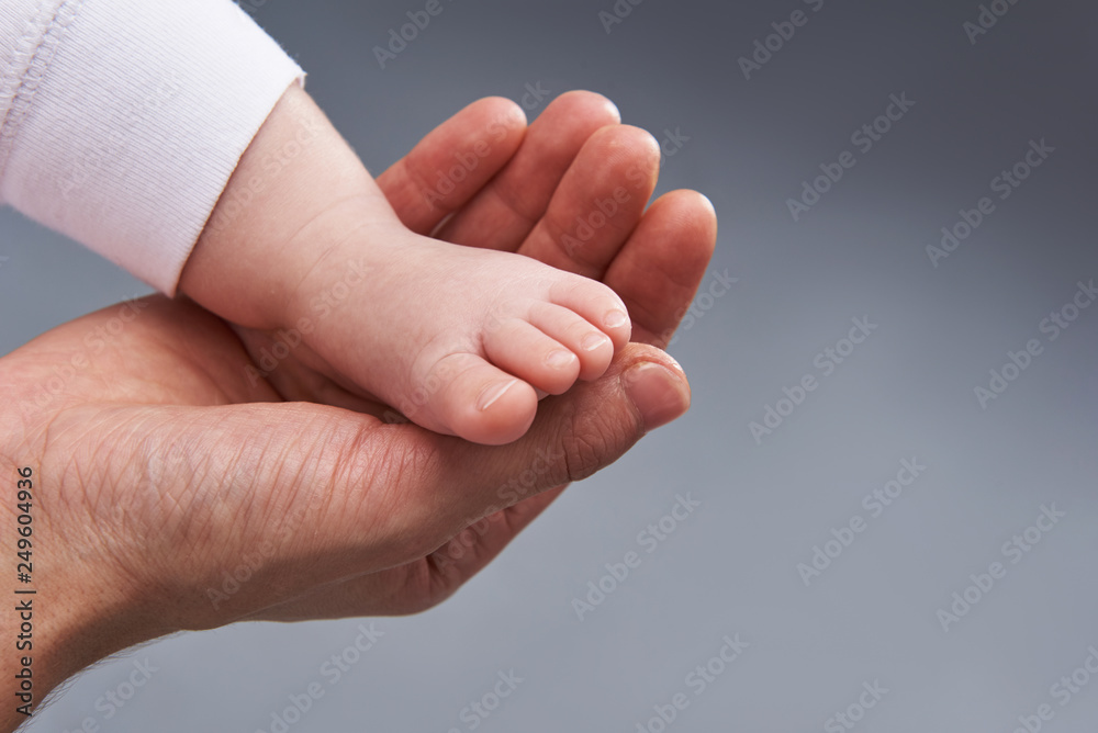 Cropped photo of woman holding little baby by the foot Cropped photo of woman holding little baby by the foot