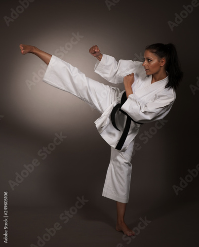 Woman in white kimono kicks high in the air - a karate martial art girl