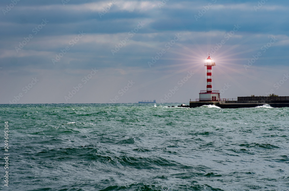Lighthouse searchlight beam through marine air. Lighthouse In Stormy Landscape - Leader And Vision Concept