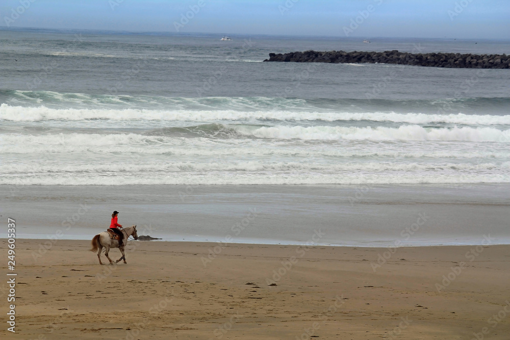 Unidentified Person Horseback Riding on Pacific Coast Beach