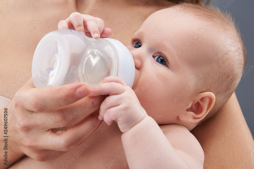 Pretty baby looking aside and sucking water from bottle Pretty baby looking aside and sucking water from bottle