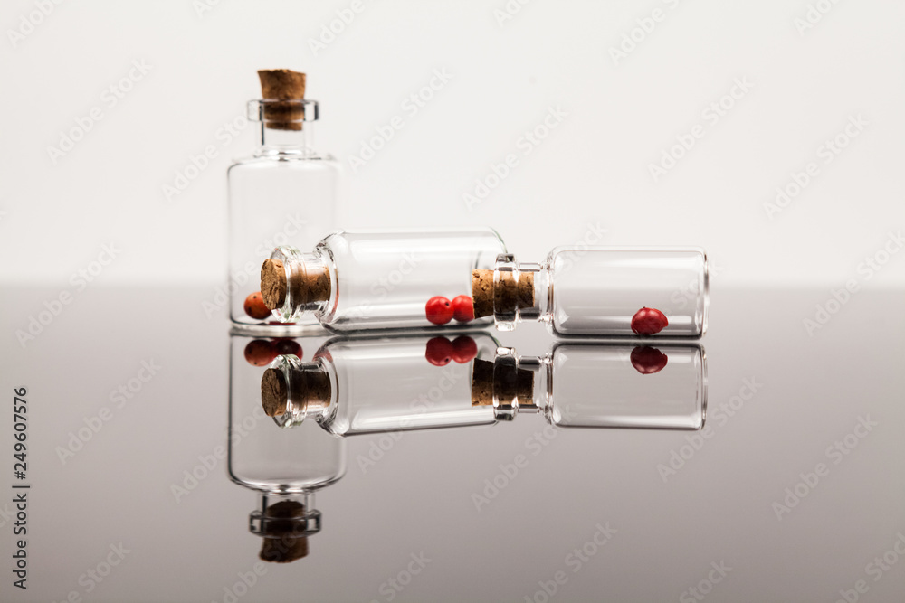 Small glass bottles with red pepper and reflexions Small glass bottles with red pepper and reflexions