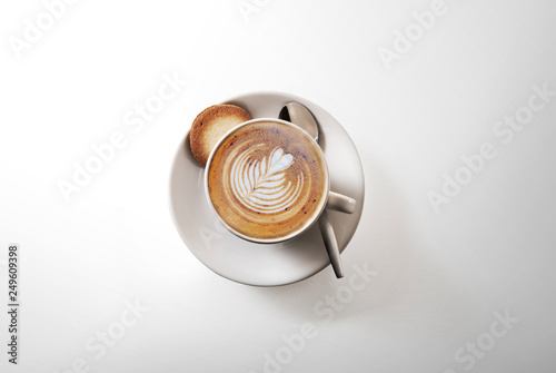 aromatic cup of Cappuccino coffee, on a saucer, with a spoon, shot from above on white, with a drop shadow photo