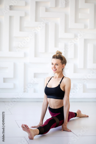 Smiling fitness woman doing gymnastics exercise while sitting on twine.