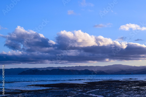 The blue sky and sea are only seperated by dark land and light clouds in Gisborne, new Zealand.