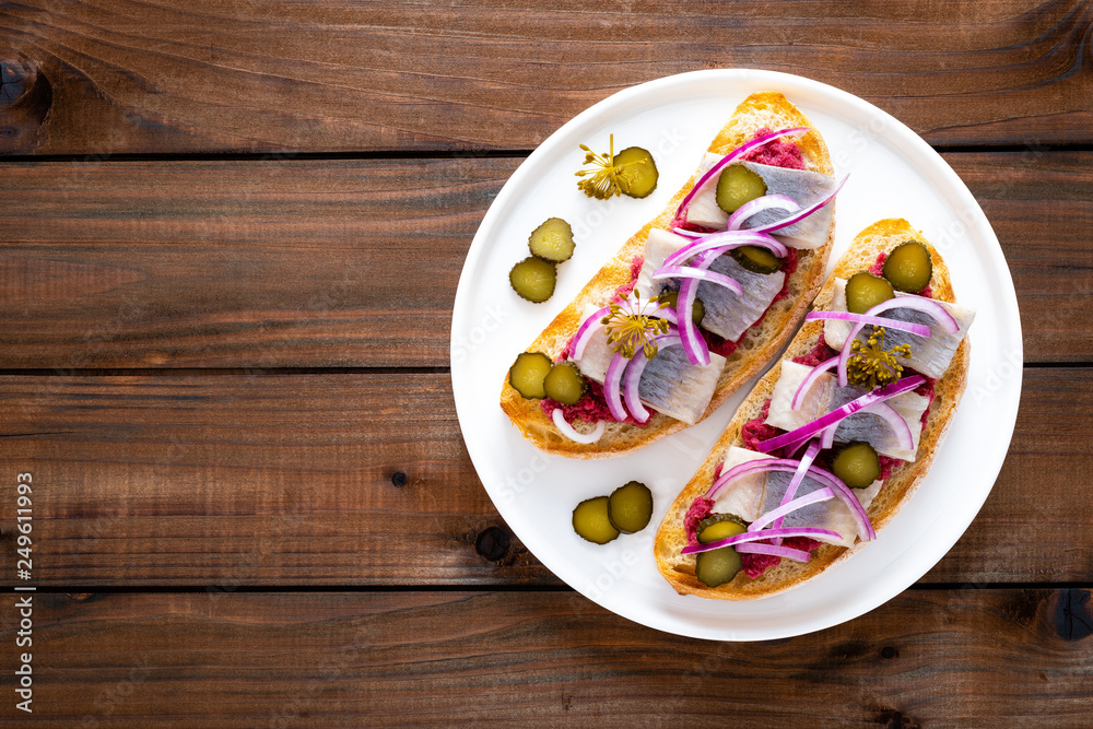 Delicious grilled sandwiches with herring, onion and beetroot sauce with horseradish on dark wooden rustic background. Danish cuisine. Top view Delicious grilled sandwiches with herring, onion and beetroot sauce with horseradish on dark wooden rustic background. Danish cuisine. Top view
