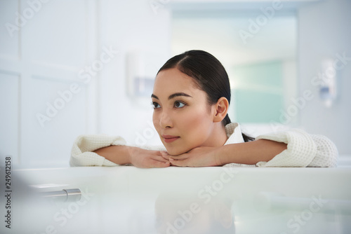 Relaxed asian lady lean on bath in beauty salon