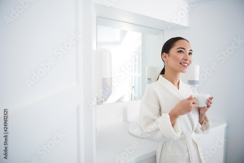 Smiling asian lady with cup of tea in beauty salon