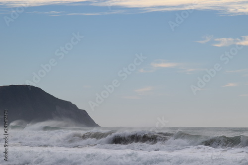 Waves crash on the shore as the cliffs stand above the beach in Gisborne, New Zealand.