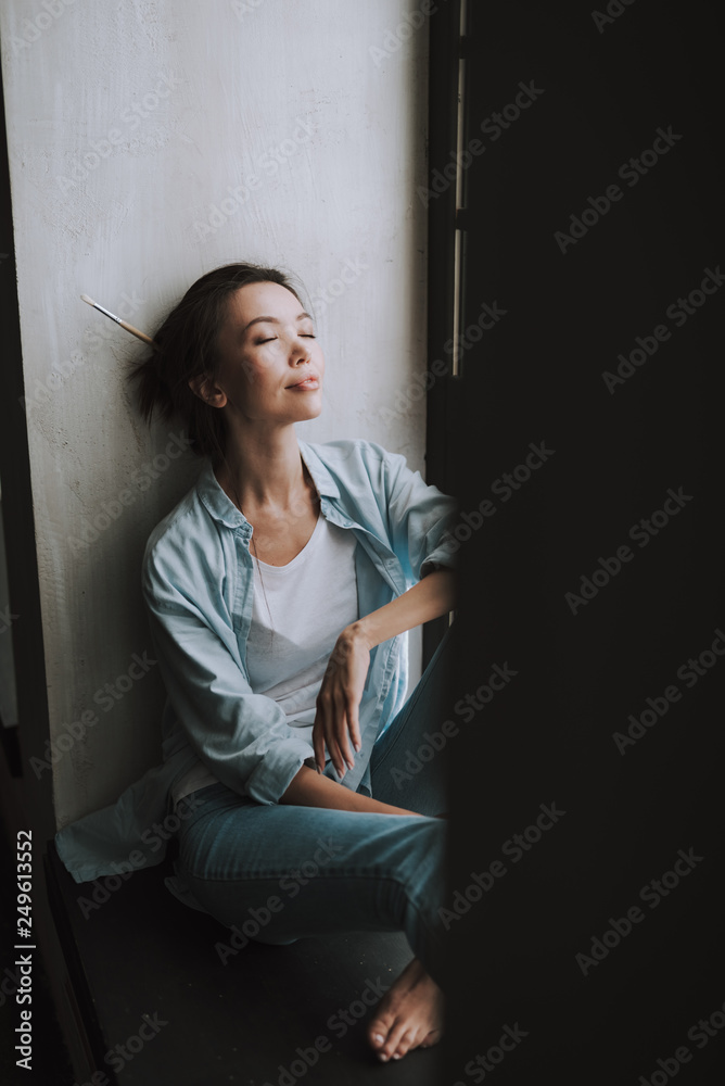 Relaxed young lady smiling while sitting with her eyes closed Relaxed young lady smiling while sitting with her eyes closed