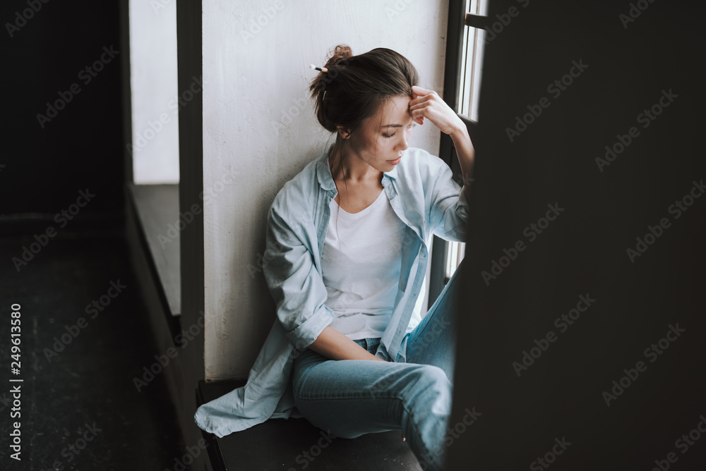 Dark haired young woman closing her eyes while sitting and thinking Dark haired young woman closing her eyes while sitting and thinking