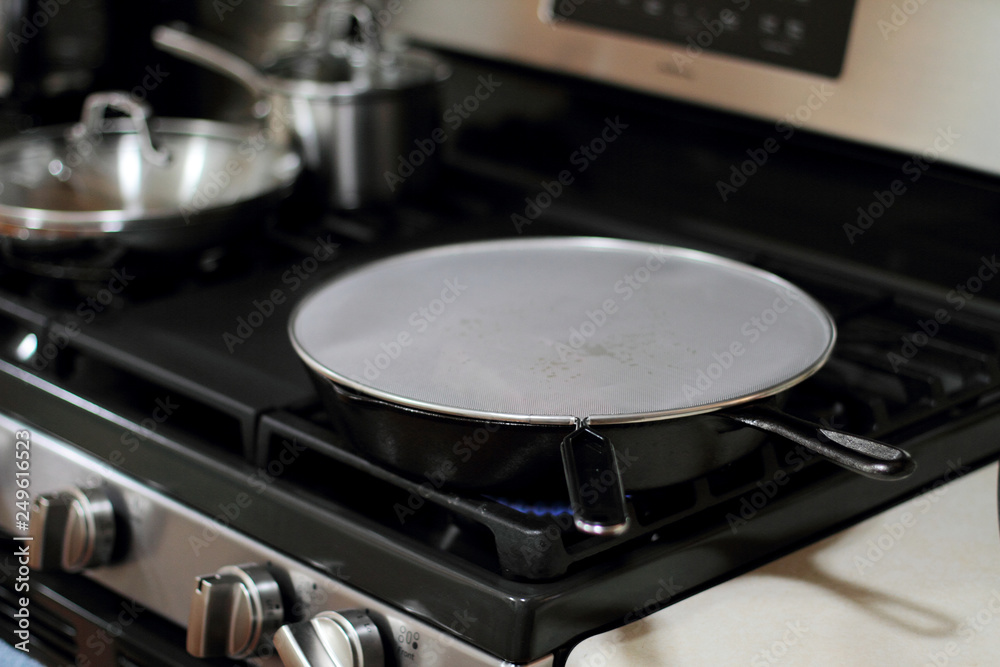 Splatter screen on cast iron pan to prevent grease mess on the stove. Splatter screen on cast iron pan to prevent grease mess on the stove.