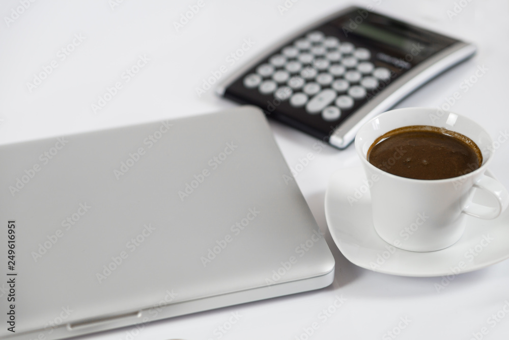 Business work place with cup of coffee calculator and closed computer laptop Business work place with cup of coffee calculator and closed computer laptop