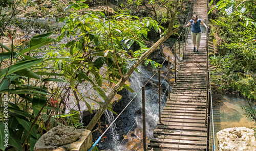 Woman on a suspension bridge over a waterfall in the rainforest of Paraguay.. photo